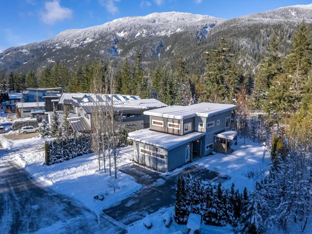 Snowy aerial view featuring a wooded view and a mountain view