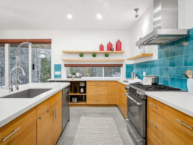 Kitchen featuring tasteful backsplash, open shelves, stainless steel appliances, wall chimney exhaust hood, and a sink