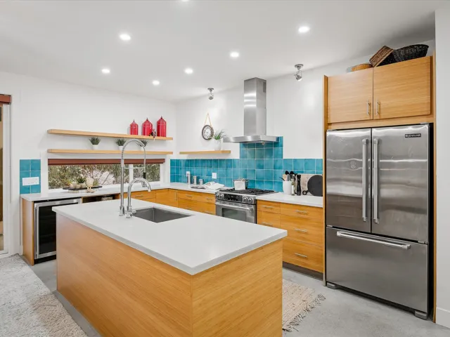 Kitchen featuring modern cabinets, a sink, stainless steel appliances, wine cooler, and wall chimney exhaust hood