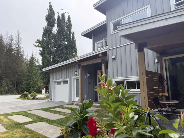 Modern exterior with vertical panel siding, an integrated garage, covered entry, and expansive windows