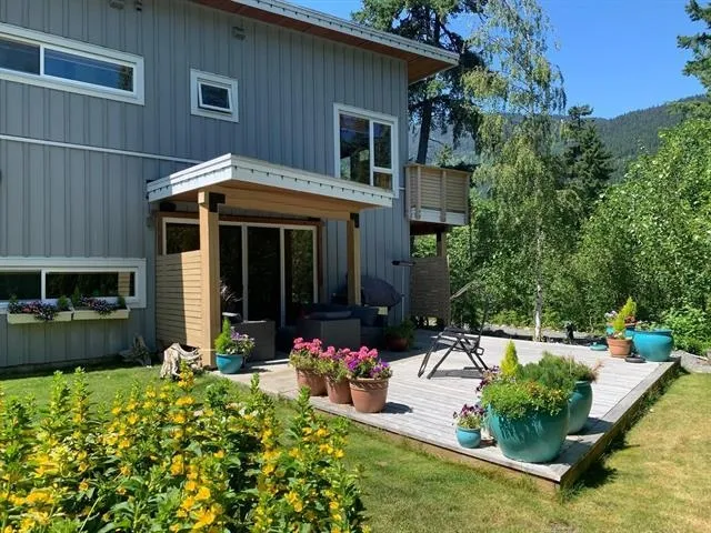 Rear view of house featuring a wooden deck, a lawn, and board and batten siding