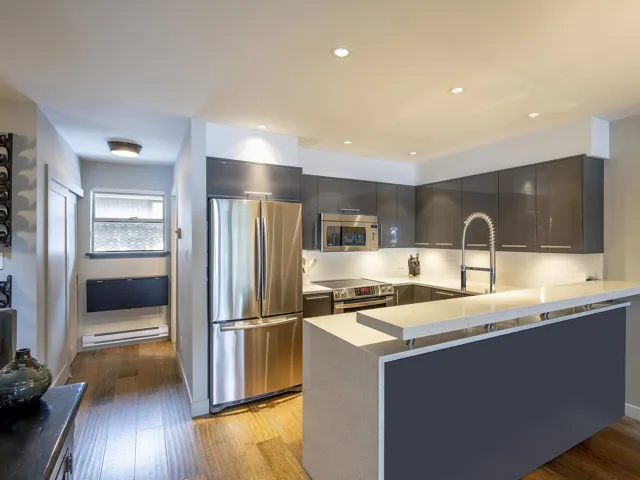 Kitchen featuring light countertops, light wood-style flooring, a peninsula, stainless steel appliances, and a baseboard heating unit