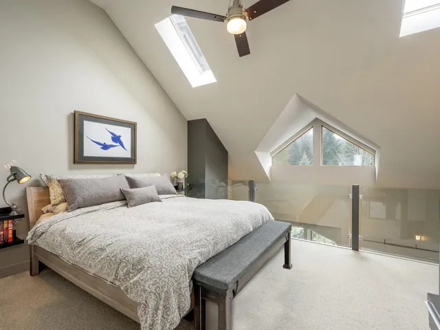 Bedroom with carpet flooring, ceiling fan, high vaulted ceiling, and a skylight