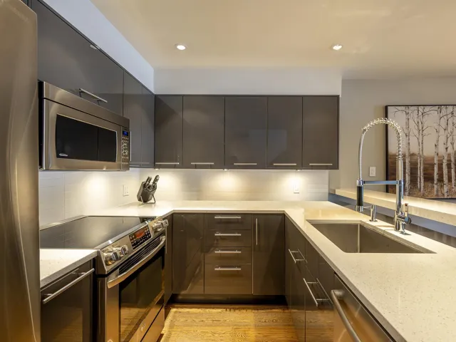 Kitchen with modern cabinets, a sink, stainless steel appliances, and light stone countertops