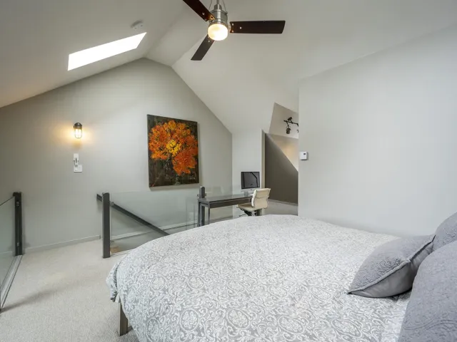 Carpeted bedroom featuring baseboards, ceiling fan, and vaulted ceiling with skylight