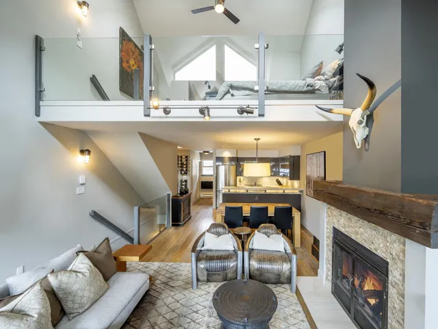 Living room featuring a tiled fireplace, stairway, a high ceiling, light wood-style floors, and ceiling fan