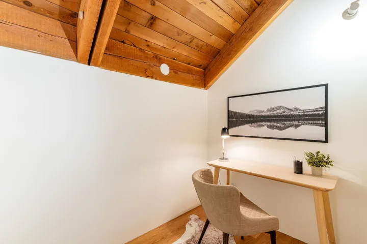 Vaulted wood-plank ceiling with exposed beams, white painted walls, and wood-finish flooring