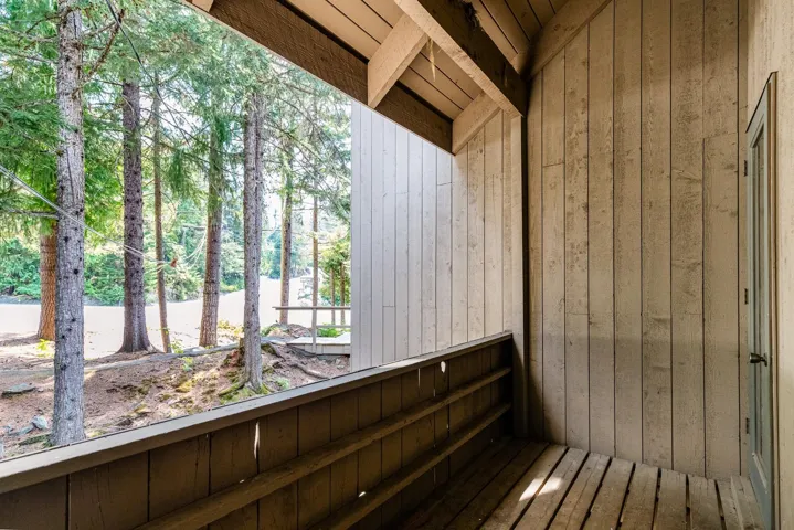 Covered outdoor space featuring wood-plank flooring, vertical wood-panel siding, and exposed wood beams
