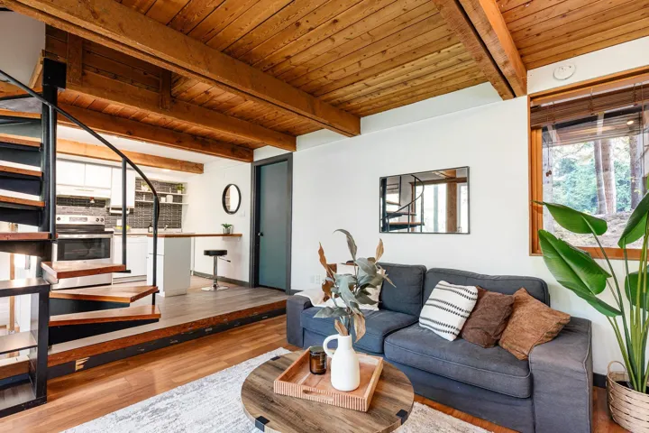 Wood-beam ceiling, spiral staircase with wood treads, wood-finish flooring, kitchen with stainless steel oven, and a built-in kitchen island