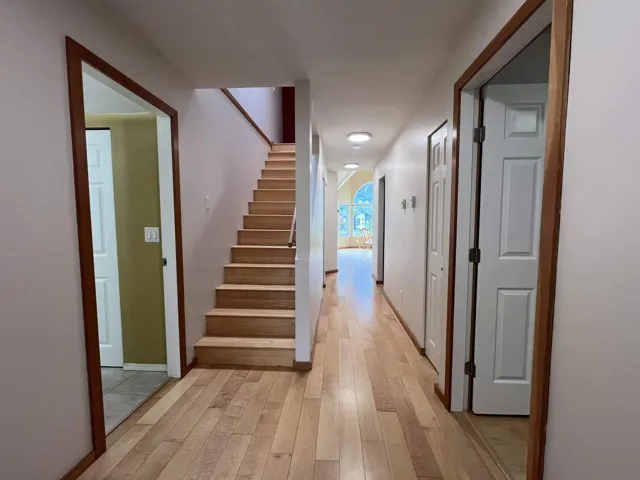 Hallway featuring light wood-style floors, stairway, and baseboards