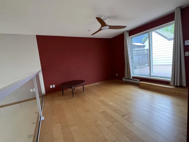 Empty room featuring baseboard heating, light wood-style floors, and a ceiling fan