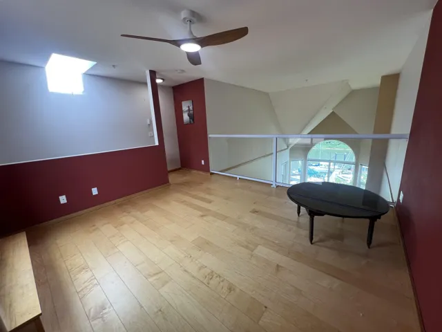 Living area with ceiling fan, wood finished floors, and baseboards