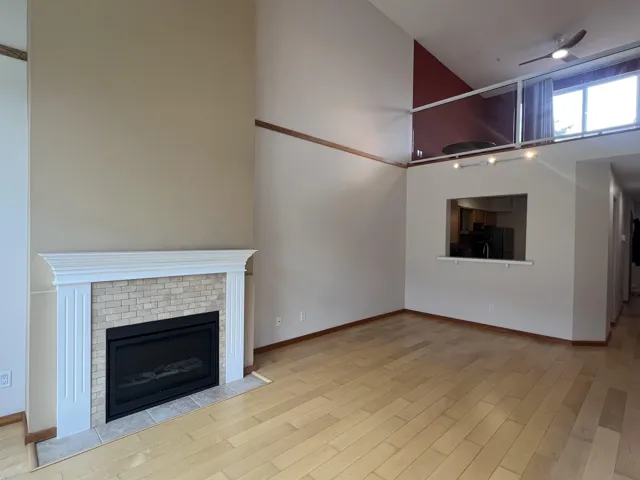 Unfurnished living room featuring wood finished floors, a fireplace, track lighting, and baseboards
