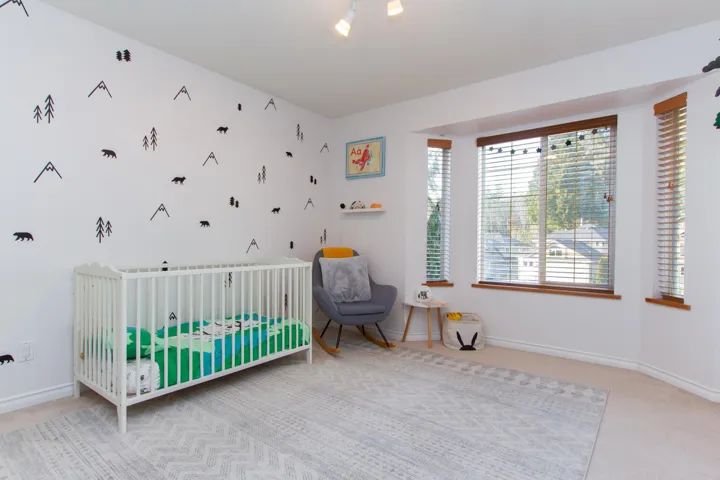 Carpeted bedroom featuring a nursery area and baseboards