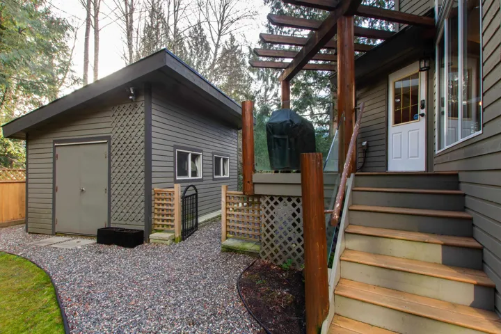 View of home's exterior with fence, a pergola, and an outbuilding