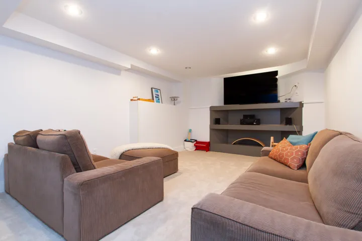 Living area with light carpet and recessed lighting