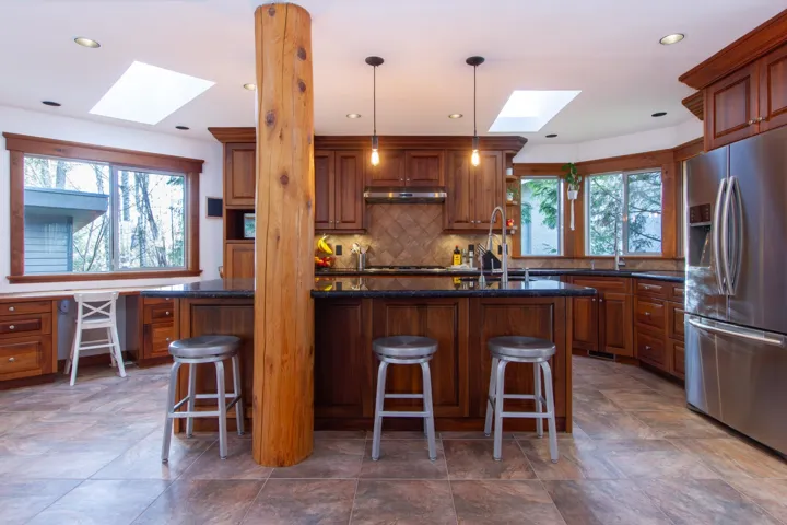 Kitchen featuring stainless steel fridge with ice dispenser, backsplash, a sink, under cabinet range hood, and a kitchen breakfast bar