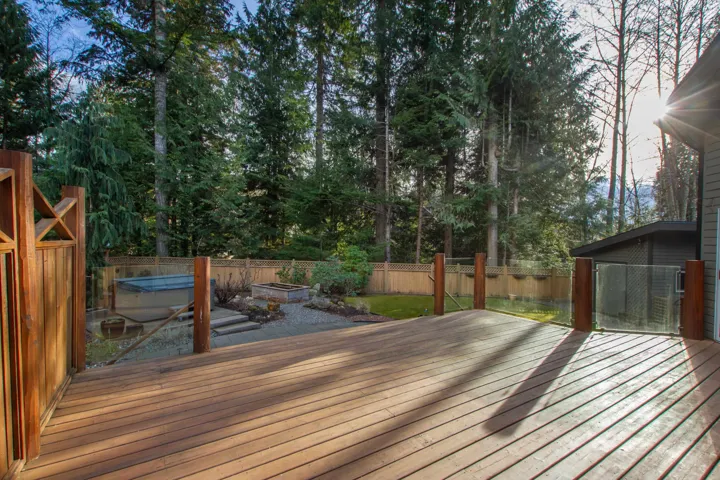 Wooden deck with a fenced backyard and a hot tub