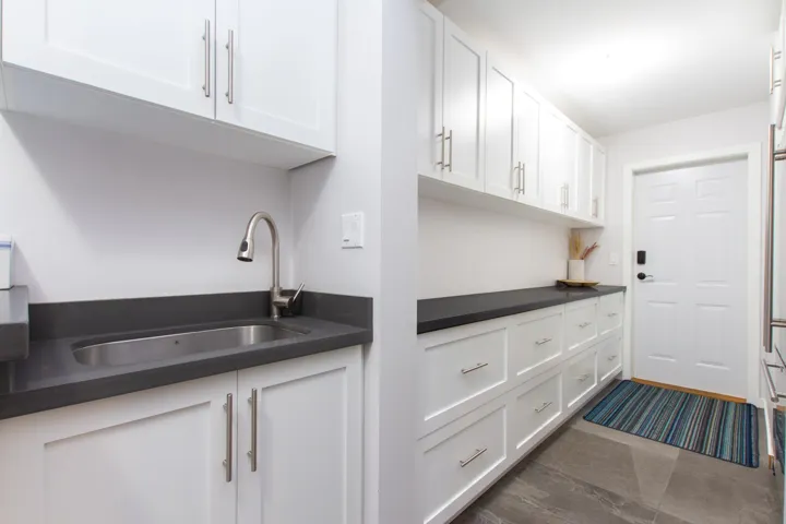 Kitchen featuring dark countertops, a sink, and white cabinetry
