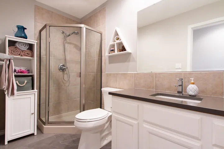 Full bathroom with toilet, a stall shower, tile walls, and vanity