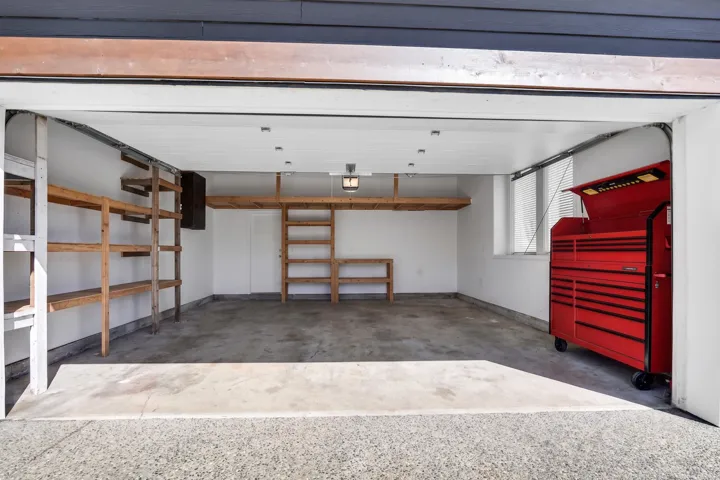 Spacious garage with concrete flooring, multiple built-in wood shelving units, overhead storage, and recessed lighting