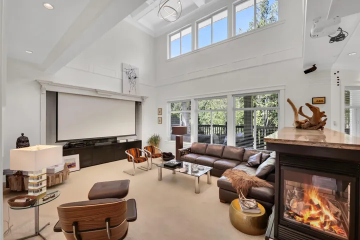 Living area featuring a large projection screen, high ceilings with decorative beams, and upper transom windows