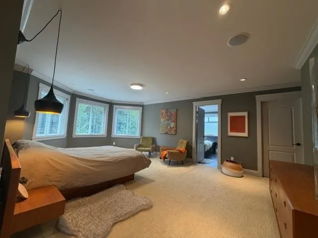 Spacious room featuring multiple windows, recessed lighting, crown molding, and light-toned carpet flooring