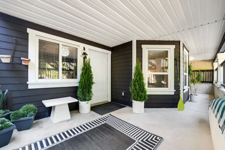 Covered outdoor patio area featuring dark siding, white trim, and a white paneled ceiling