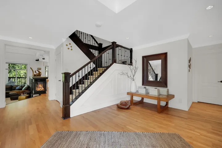 Hardwood flooring spanning the entry, featuring a dark wood and wrought iron staircase with white wainscoting