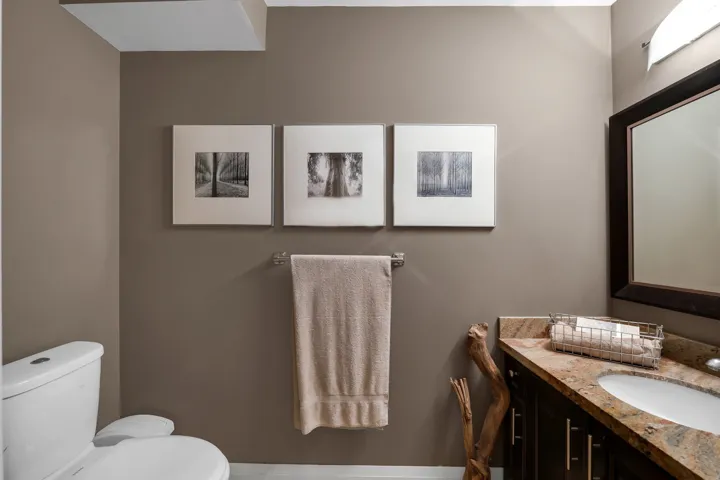 Bathroom featuring a built-in vanity with a stone countertop, an integrated sink, and an expansive wall mirror with a dark frame