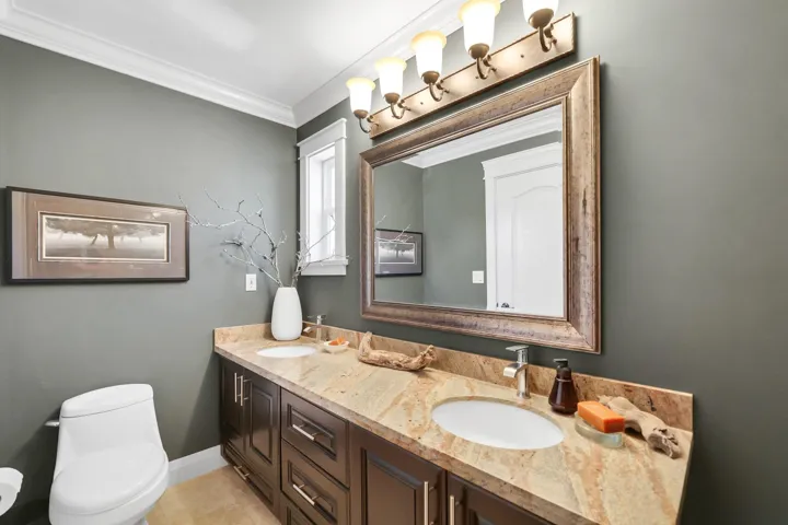 Double vanity featuring a granite countertop with two undermount sinks, flanked by dark wood-finish cabinetry