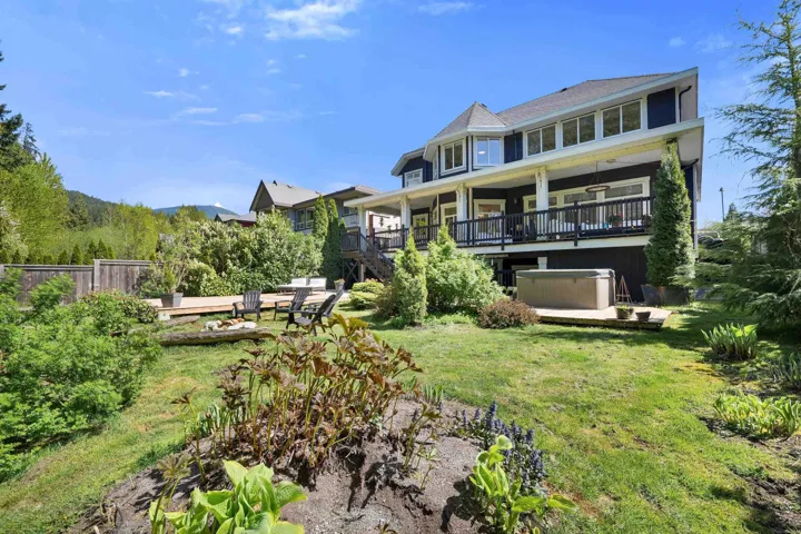 Expansive backyard featuring a multi-level deck, lush landscaping, and a hot tub