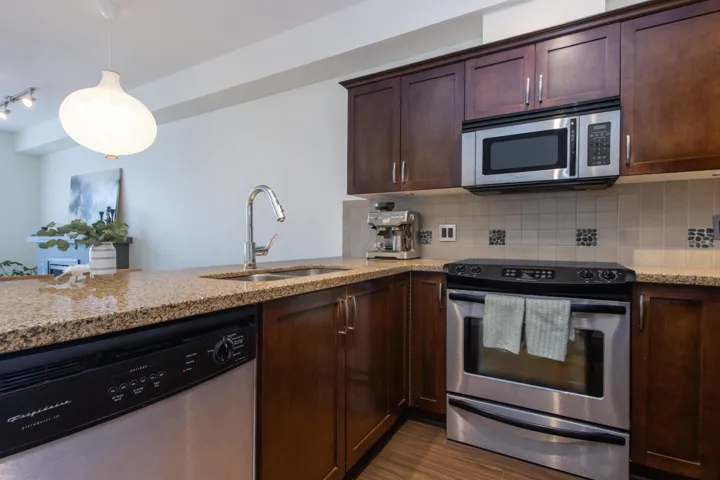 Kitchen featuring tasteful backsplash, appliances with stainless steel finishes, a sink, and light stone counters