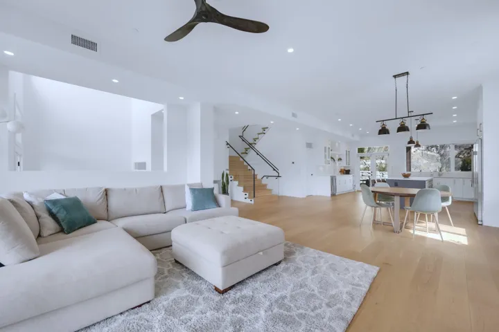 Living area featuring light wood finished floors, visible vents, recessed lighting, and stairs