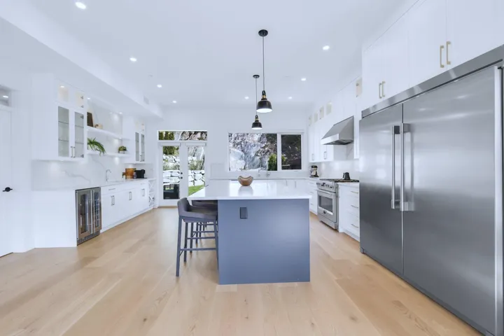 Kitchen with a center island, premium appliances, white cabinetry, wall chimney range hood, and beverage cooler
