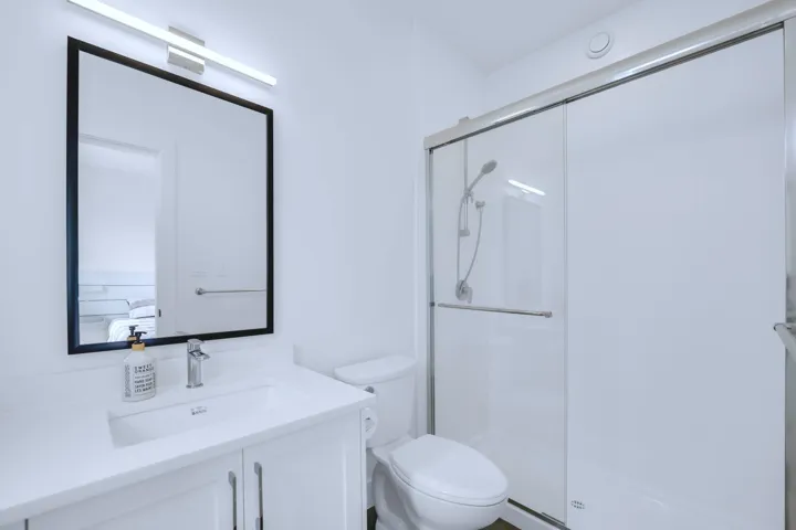 Ensuite bathroom with ensuite bath, toilet, vanity, and a stall shower