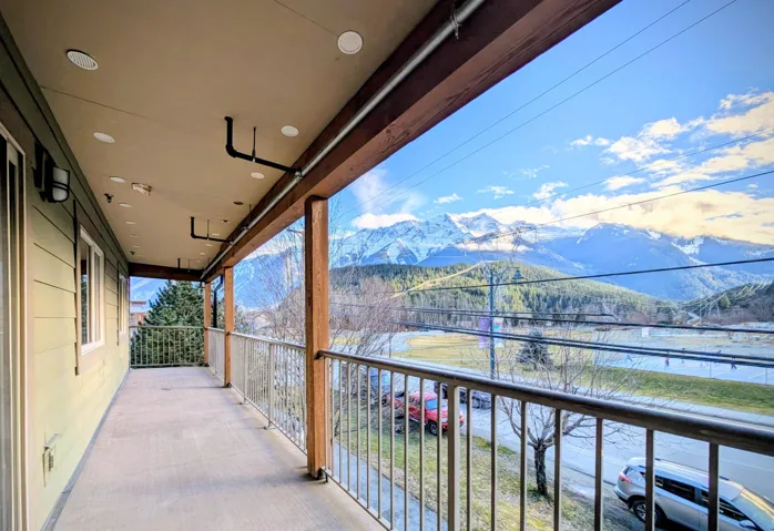 Expansive covered balcony featuring a light green siding exterior, recessed lighting, and metal railings