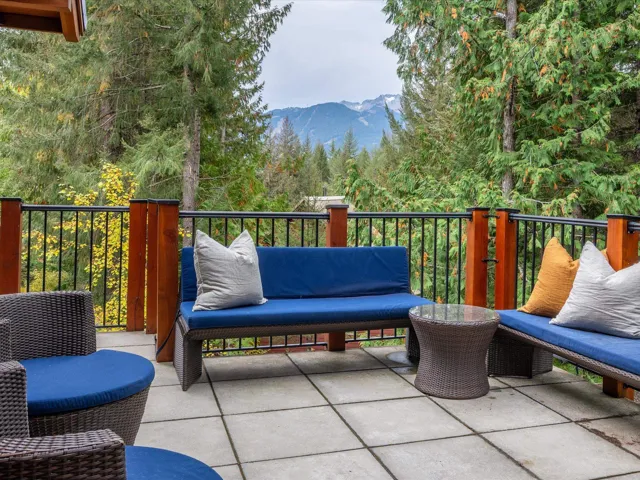 Spacious outdoor patio featuring large format pavers and a metal railing with wood posts