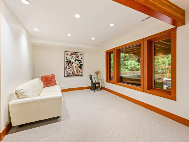 Recessed lighting illuminates this room featuring light-toned carpeting and wood-trimmed windows