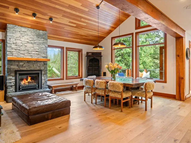 Great room featuring a stone-clad fireplace with a wood mantel, vaulted wood-plank ceiling, exposed wood beams, and light wood-finish flooring