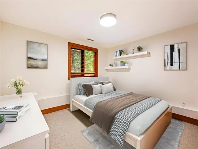 Carpeted room featuring a window with wood blinds, a ceiling-mounted light fixture, and two wall-mounted shelves