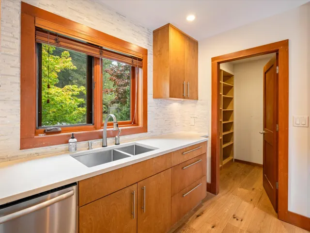 Kitchen featuring wood-finish cabinetry, light-toned countertops, and a dual basin stainless steel sink with a gooseneck faucet