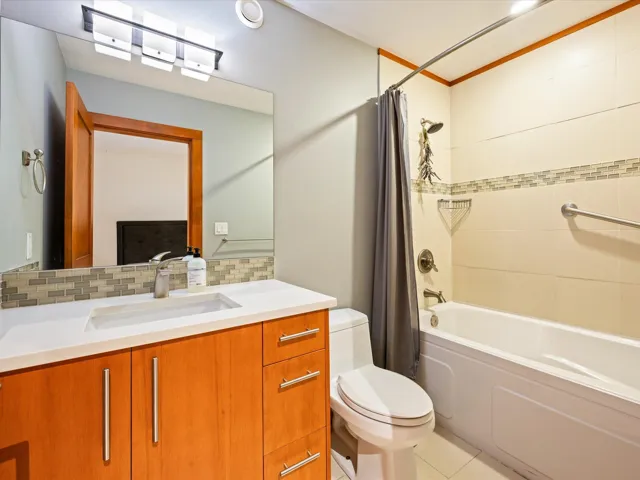 Bathroom featuring a wood-finish vanity with a white countertop and integrated sink, a rectangular mirror, and a wall-mounted light fixture