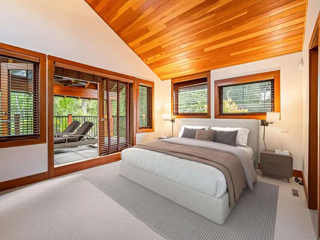 Vaulted wood-paneled ceiling accentuating a spacious room with light-toned carpeting