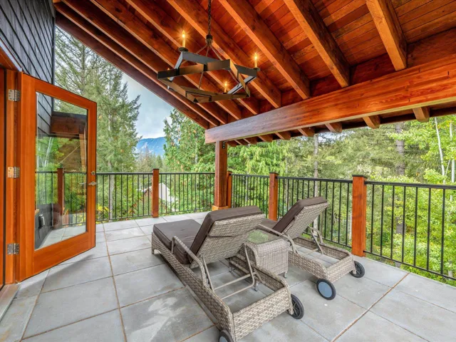 Expansive outdoor deck featuring substantial wood beams, a matching wood ceiling, and a large iron chandelier
