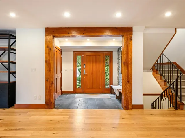 Entryway featuring a solid wood door with sidelight windows, slate tile flooring, and exposed wood beam accents