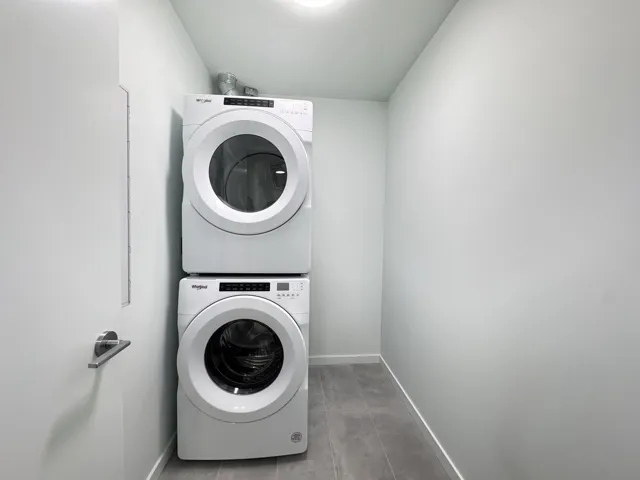 Laundry area with baseboards and estacked washer and dryer