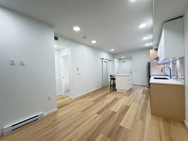Kitchen with a barn door, a kitchen breakfast bar, baseboard heating, a center island, and white cabinetry