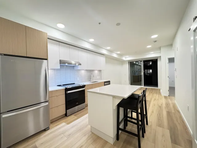 Kitchen with white cabinets, stainless steel appliances, a kitchen breakfast bar, decorative backsplash, and modern cabinets