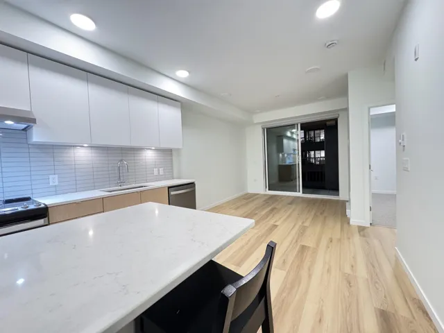 Kitchen with modern cabinets, backsplash, white cabinetry, light stone countertops, and recessed lighting